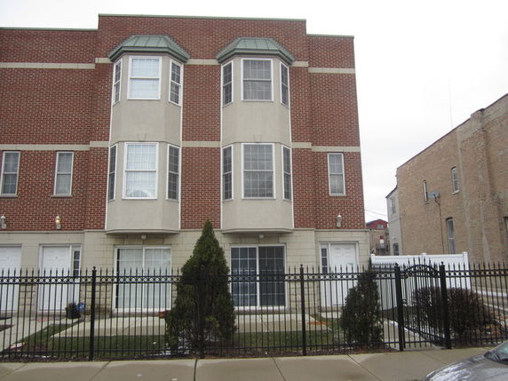 Front view of a multi-story apartment building with brick facade and bay windows.