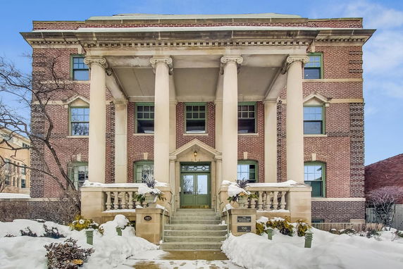 Front view of a large brick building with prominent columns and green-trimmed windows.
