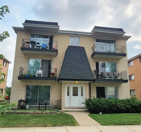 Front view of a three-story apartment building with balconies.