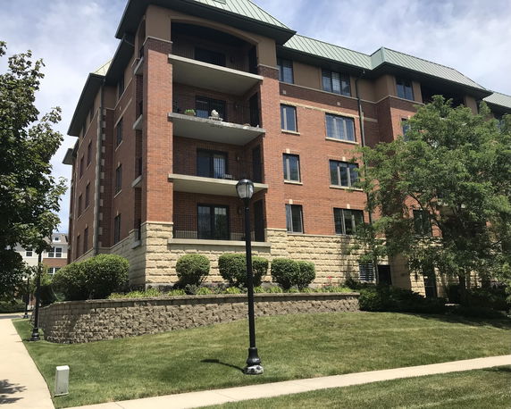 Front view of a multi-story apartment building with balconies and a brick exterior.