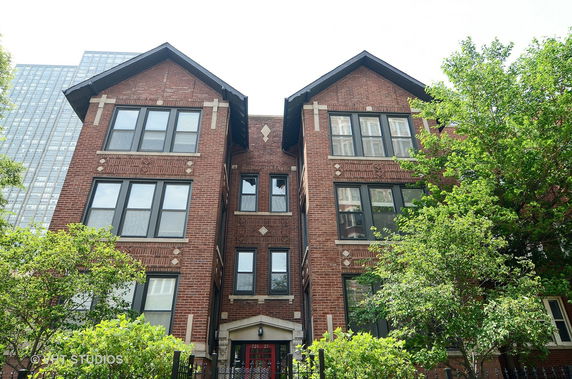 Front view of a multi-story brick building with large windows and decorative details.