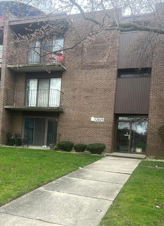 Front view of a multi-story brick building with balconies and an entrance.