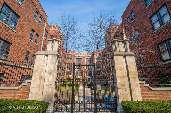 Front view of a red brick multi-story residential building with gated entrance.