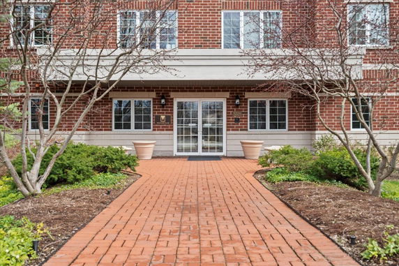 Front view of a brick apartment building with a glass door entrance.
