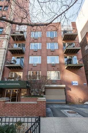 Front view of a mid-rise condominium building with balconies and brick exterior.