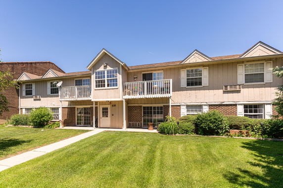 Front view of a two-story residential building with balconies and a sloped roof.
