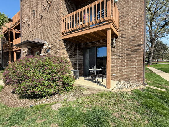 Front view of a two-story brick building with balconies and a small patio area.