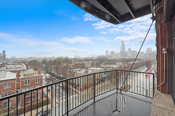 Panoramic view of cityscape from a balcony with railing.