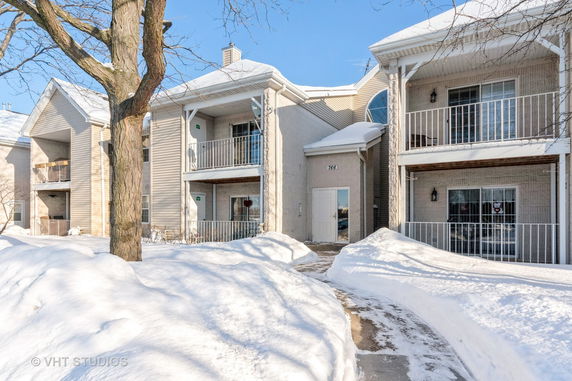 Front view of a multi-story residential building with balconies, in a snowy environment.