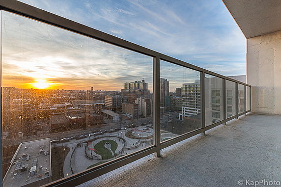 Panoramic view from a balcony overlooking a cityscape during sunset.