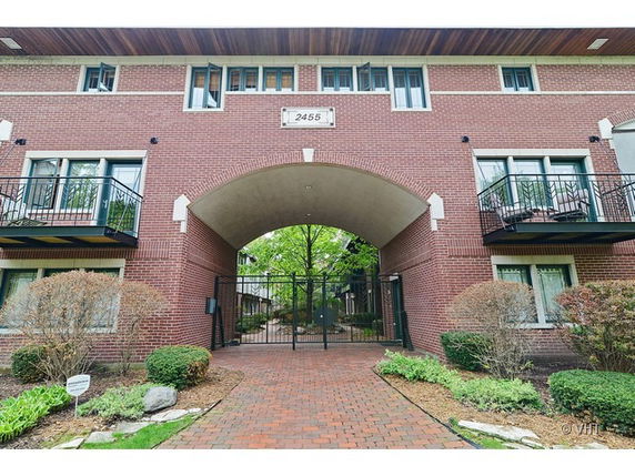 Front view of a brick building with an arched entrance and balconies.