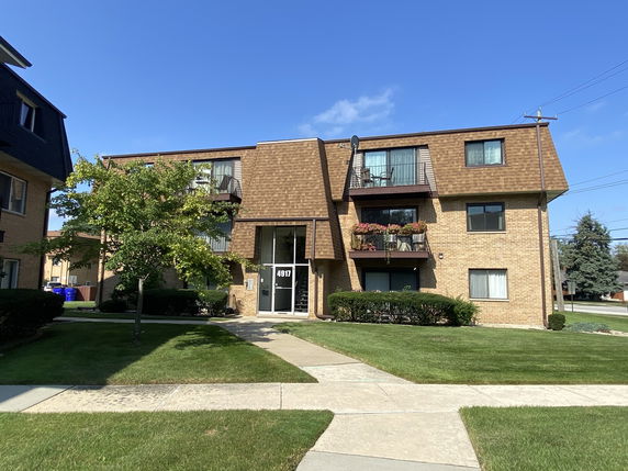 Front view of a two-story apartment building with balconies and brick exterior.