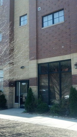 Front view of a multi-story building with brick facade and large windows.