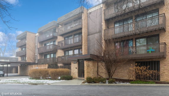Front view of a multi-story brick apartment building with balconies.