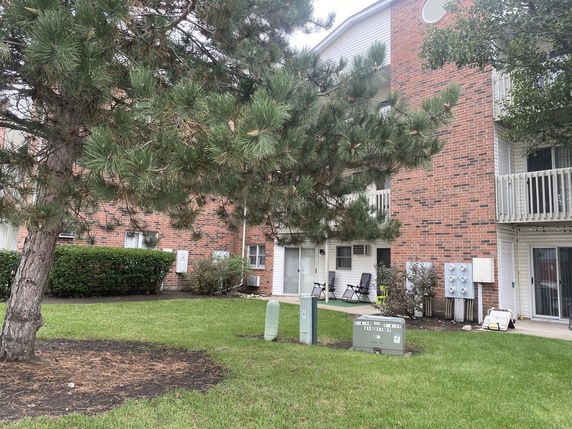 Front view of a brick residential building with balconies and outdoor seating.