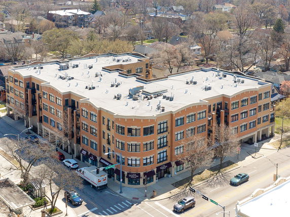 Front view of a multi-story building with a brick facade and flat rooftop, located at the corner of a street intersection.