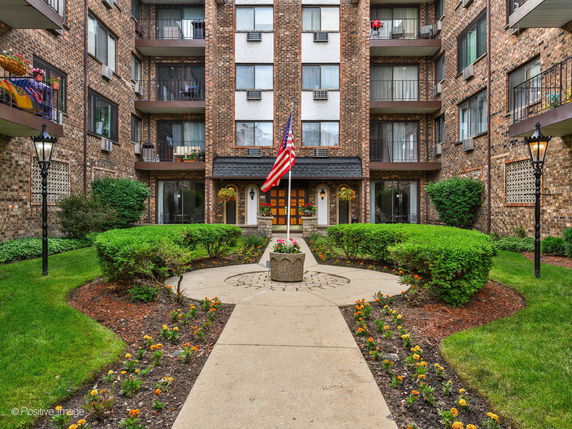 Front view of a multi-story brick apartment building with balconies.