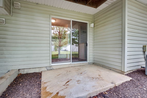Back patio area with sliding glass door and concrete slab.