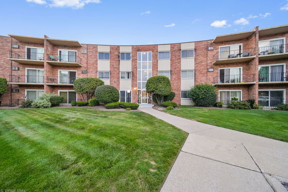 Front view of a multi-story brick apartment building with balconies.