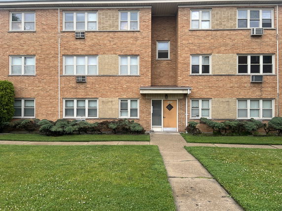 Front view of a three-story brick apartment building with multiple windows and a central entrance.