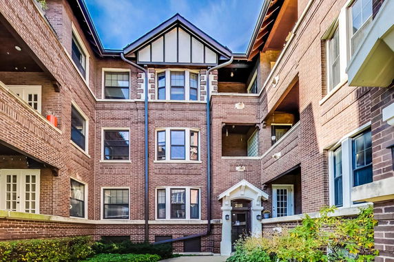 Front view of a multi-story brick apartment building with balconies.