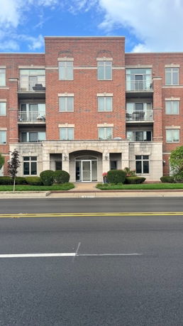 Front view of a multi-story building with brick facade and balconies.
