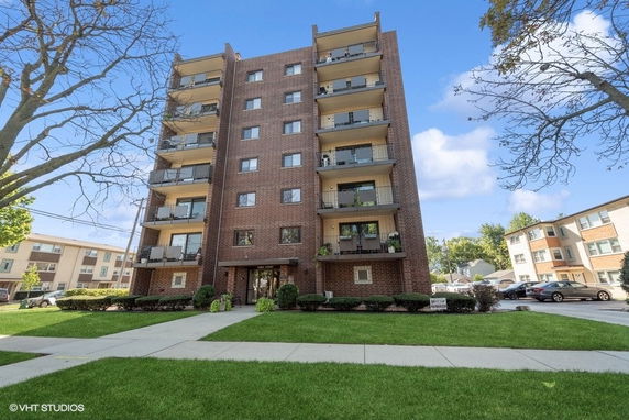 Front view of a multi-story brick apartment building with balconies.