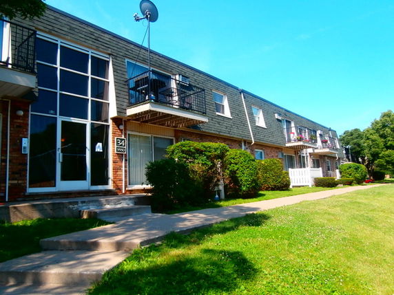 Front view of a multi-story residential building with balconies and a satellite dish.