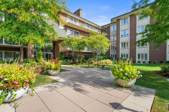 Front view of a multi-story brick residential building with balconies and landscaped garden.
