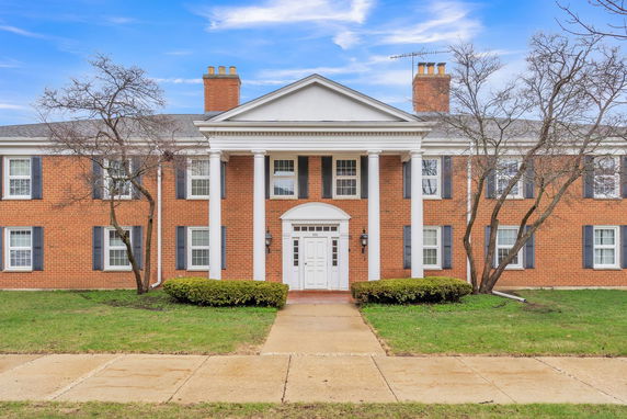 Front view of a two-story brick building with columns and symmetrical windows.
