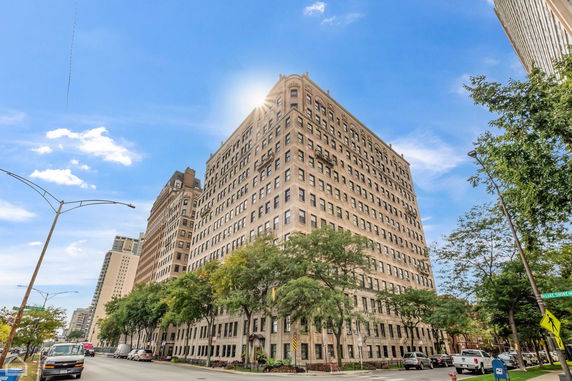 Front view of a large multi-story residential building on a city street corner.