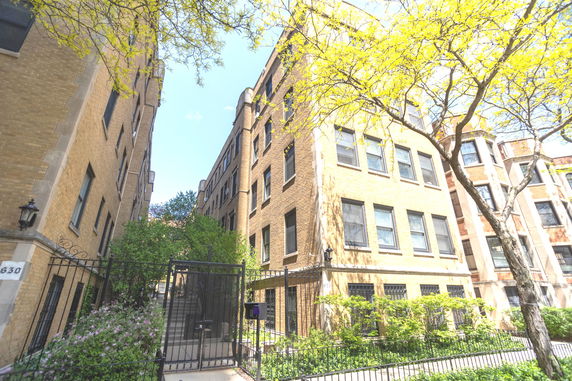 Front view of a multi-story brick building with gated entrance.