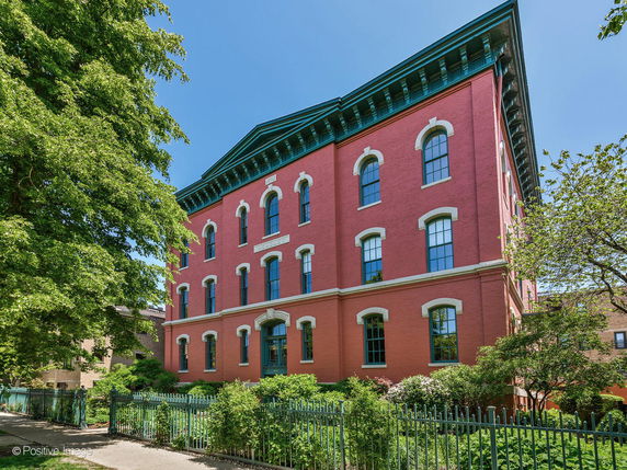 Front view of a three-story red brick building with arched windows.