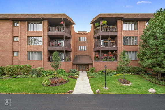 Front view of a multi-story brick residential building with balconies.