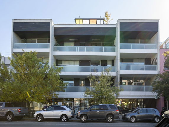 Front view of a modern multi-story apartment building with balconies.