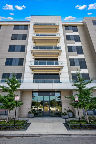 Front view of a multi-story building with several balconies and a glass entrance.