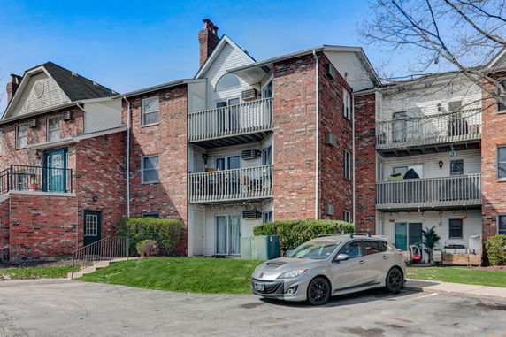 Front view of a multi-story apartment building with brick exterior and balconies.