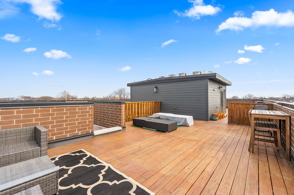 Rooftop with wooden flooring, seating area, and covered furniture.