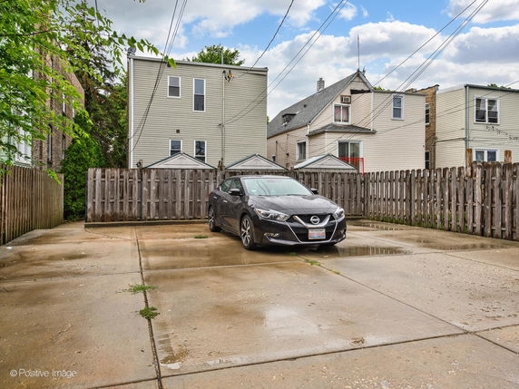 Outdoor parking area with a single parked car and surrounding residential buildings.