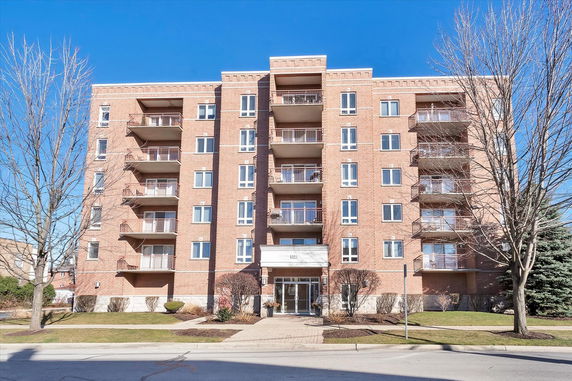 Front view of a multi-story brick apartment building with balconies.
