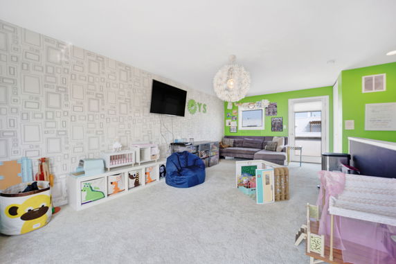 Children's indoor playroom with bright walls, storage units, and seating area.