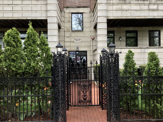 Front view of a multi-story building with a gated entrance.
