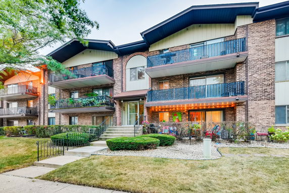 Front view of a multi-story apartment building with balconies and brick exterior.