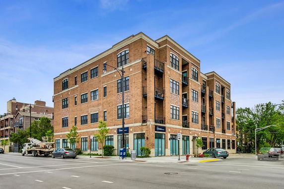 Front view of a multi-story brick building on a street corner.