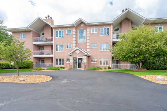 Front view of a multi-story residential building with balconies and a pitched roof.