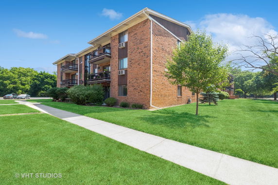 Front view of a multi-story brick apartment building with balconies.