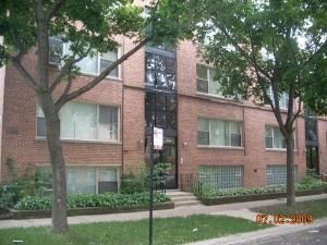 Front view of a three-story brick apartment building with large windows.