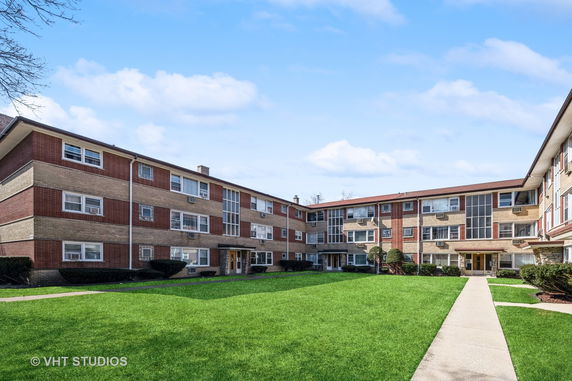 Front view of a multi-story residential building with a courtyard.