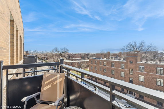 View from a building balcony overlooking urban landscape and distant city skyline.