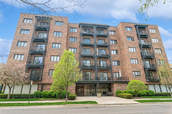 Front view of a multi-story brick apartment building with balconies.